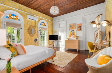 Marrero's Guest Mansion gay-friendly hotel room. Bright yellow walls, wood floors, & eclectic decor. Comfortable, stylish gay travel lodging.