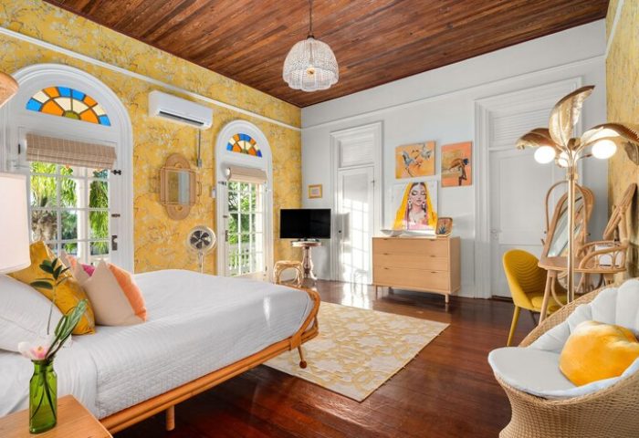 Marrero's Guest Mansion gay-friendly hotel room. Bright yellow walls, wood floors, & eclectic decor. Comfortable, stylish gay travel lodging.