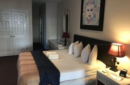 Bedroom interior at a gay-friendly hotel in New Orleans. Queen bed with white linens, bedside lamps, and unique wall art. Comfortable stay.