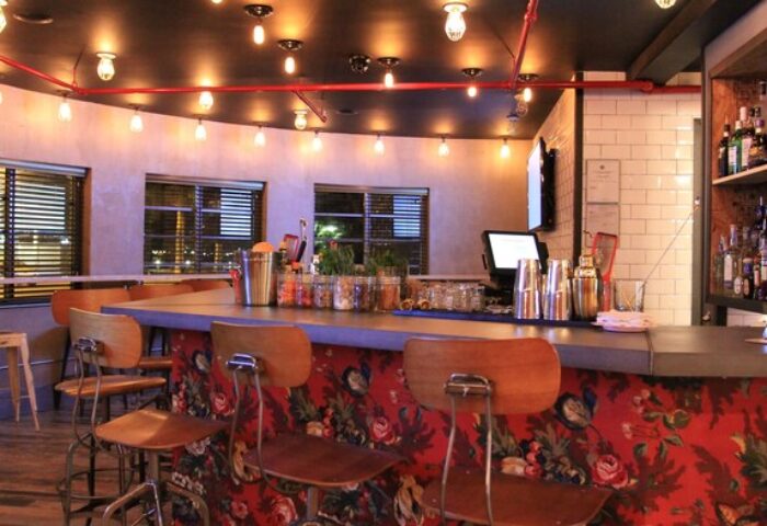 Gaythering's bar area with crates, offering a welcoming space in a gay-friendly hotel. View of the bar with chairs and liquor bottles.