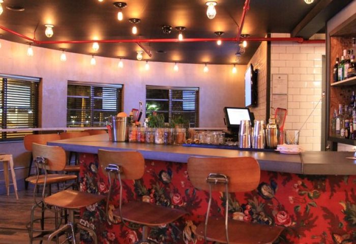 Gaythering's bar area with crates, offering a welcoming space in a gay-friendly hotel. View of the bar with chairs and liquor bottles.