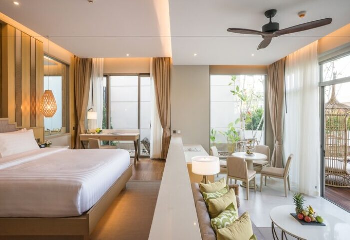 Avani+ Hua Hin Resort room. Gay-friendly hotel with bedroom, desk, living area, balcony, dining table, and ceiling fan. Modern design, bright, welcoming.