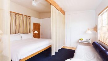 The Standard Miami gay-friendly hotel room. Minimalist design with a bed, couch, and white walls. A relaxing space for gay travel.