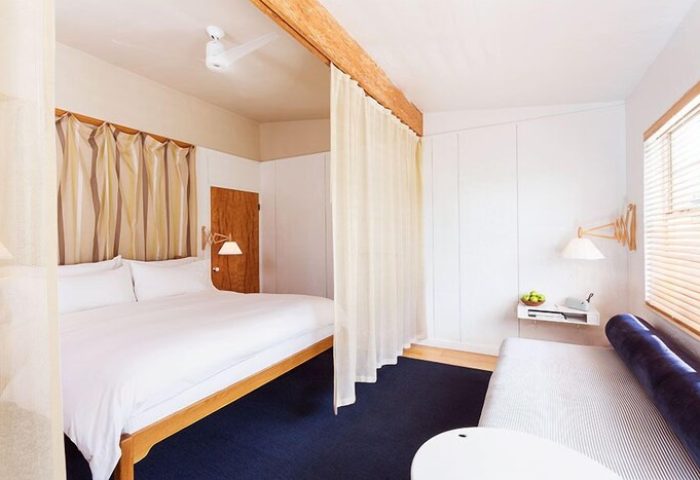 The Standard Miami gay-friendly hotel room. Minimalist design with a bed, couch, and white walls. A relaxing space for gay travel.