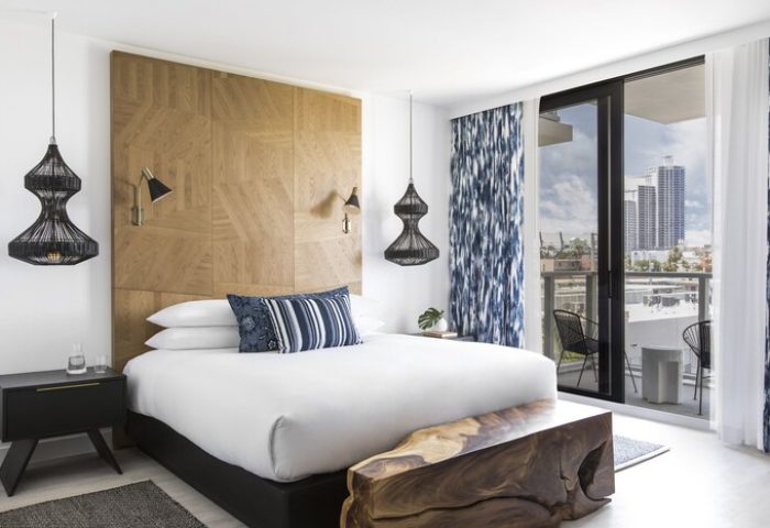 Kimpton Angler's Hotel gay-friendly room. Modern bedroom with balcony, city view, wood headboard, and unique lighting. Stylish gay travel lodging.