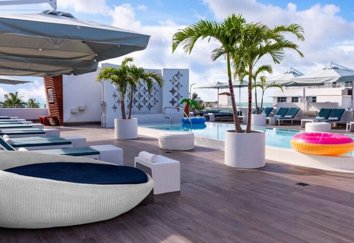 Dream South Beach gay-friendly hotel pool. Rooftop view with lounge chairs, palm trees, and colorful floaties. Part of Hyatt, Miami travel.