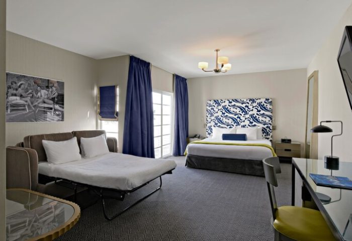 Hotel Breakwater South Beach room with king bed, pullout sofa, desk, and blue accents. Gay-friendly hotel room interior.
