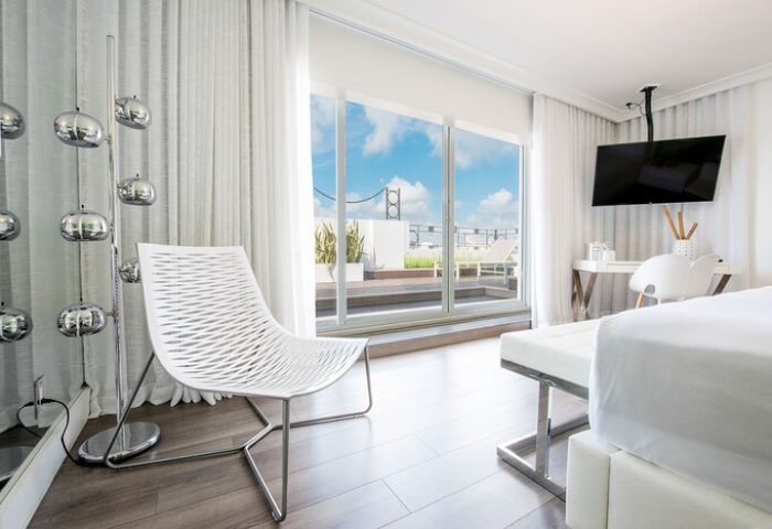 President Hotel gay-friendly room with white chair, desk, and balcony. Modern, clean design for gay men's travel. Perfect for a relaxing stay.