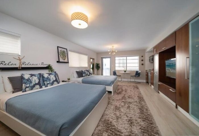 Strand Ocean Drive Suites gay-friendly hotel room with two beds, a rug, and a table with chairs. Modern design for gay men's travel advice.