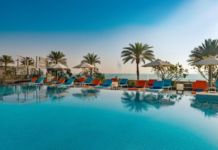 Aloft Palm Jumeirah gay-friendly hotel pool view. Palm trees, lounge chairs, and Dubai skyline. Perfect for gay travel and relaxation.