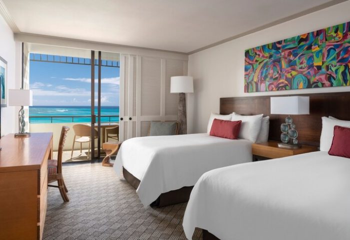 Royal Hawaiian, a Luxury Collection Resort, Waikiki gay-friendly hotel room with ocean view balcony. Two beds, colorful art, desk, chairs.