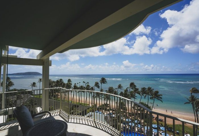 Balcony view at The Kahala Hotel and Resort, a gay-friendly hotel. Ocean, beach, and palm trees visible. Ideal for gay travel.