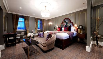 Cameron House on Loch Lomond gay-friendly hotel room. Luxury suite with sofa, desk, and floral headboard. Upscale gay travel lodging.