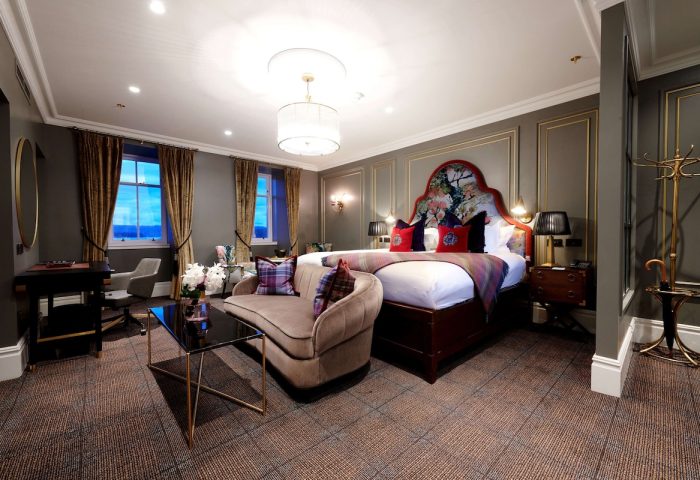 Cameron House on Loch Lomond gay-friendly hotel room. Luxury suite with sofa, desk, and floral headboard. Upscale gay travel lodging.