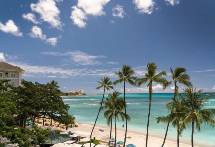 Moana Surfrider, A Westin Resort & Spa, Waikiki Beach view. Gay-friendly hotel with palm trees, white sand beach, and turquoise ocean.