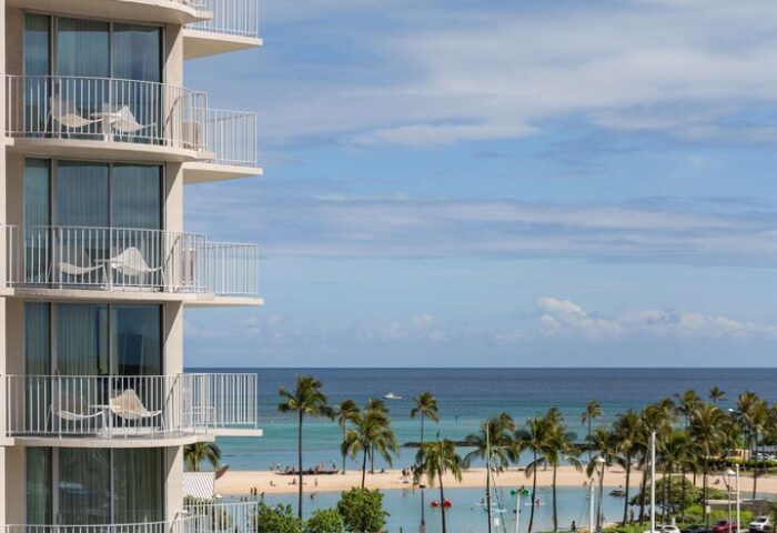 Balconies at The Modern Honolulu, a gay-friendly hotel. Ocean view with palm trees. Perfect for gay men's vacation in Honolulu.