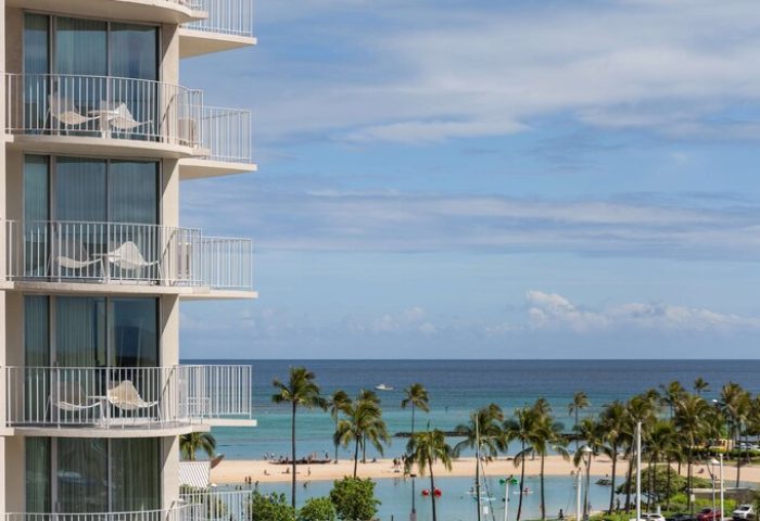 Balconies at The Modern Honolulu, a gay-friendly hotel. Ocean view with palm trees. Perfect for gay men's vacation in Honolulu.