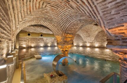 Hagia Sofia Mansions Istanbul gay-friendly hotel spa. Curio Collection by Hilton Turkish bath with brick arches and waterfall feature.