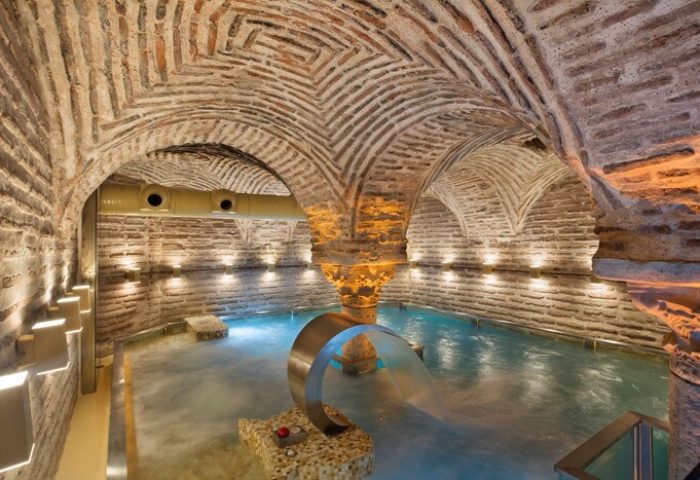 Hagia Sofia Mansions Istanbul gay-friendly hotel spa. Curio Collection by Hilton Turkish bath with brick arches and waterfall feature.