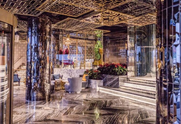 Elysium Taksim Hotel's luxurious lobby. This gay-friendly hotel features marble floors, mirrored pillars, and ornate gold ceiling designs.