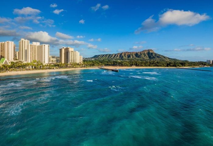 Waikiki Beach Marriott Resort & Spa: Gay-friendly hotel view of Diamond Head, turquoise ocean, sandy beach, and high-rise buildings in Honolulu.