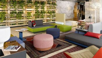 Interior of gay-friendly 25Hours Bikini Berlin hotel lounge with colorful seating, rugs, and a vertical garden wall. Modern design.