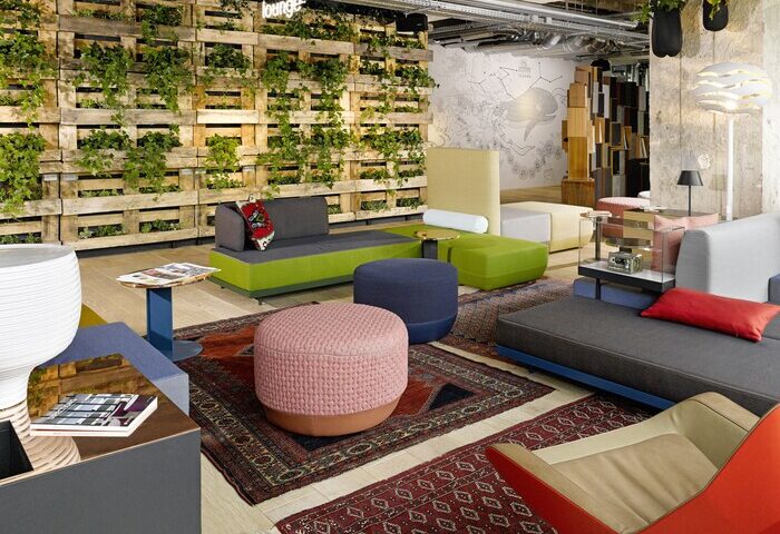 Interior of gay-friendly 25Hours Bikini Berlin hotel lounge with colorful seating, rugs, and a vertical garden wall. Modern design.