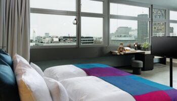 25Hours Bikini Berlin hotel room view. Gay-friendly hotel with city view, desk, and colorful bedspread. Modern design in Berlin.