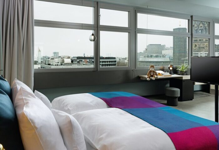 25Hours Bikini Berlin hotel room view. Gay-friendly hotel with city view, desk, and colorful bedspread. Modern design in Berlin.
