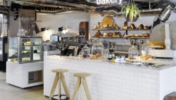 Bakery at 25Hours Bikini Berlin, a gay-friendly hotel. The stylish counter displays pastries and bread. A neon bakery sign hangs above.