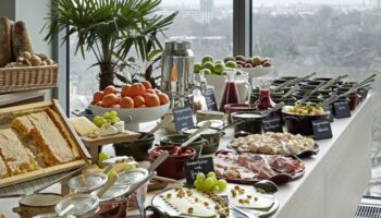 Breakfast buffet at 25Hours Bikini Berlin, a gay-friendly hotel. Features fresh fruit, cheese, meats, bread, and honeycomb. City view.