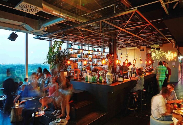 Interior of 25Hours Bikini Berlin, a gay-friendly hotel. Guests at the bar, enjoying drinks. Great view from this Berlin hotel.
