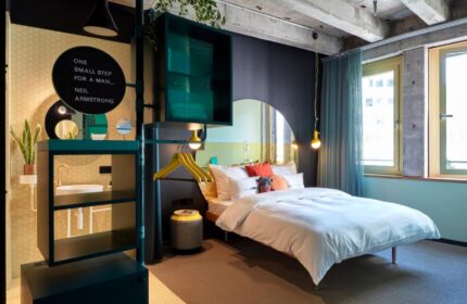 25hours Hotel The Circle room. Modern design, bed, & Neil Armstrong quote. Gay-friendly hotel in Cologne, Germany. Unique travel for gay men.