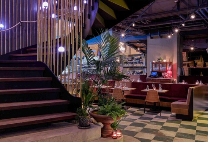 Interior of the gay-friendly 25hours Hotel The Royal Bavarian: staircase, seating, checkered floor, and plants. Upscale design.
