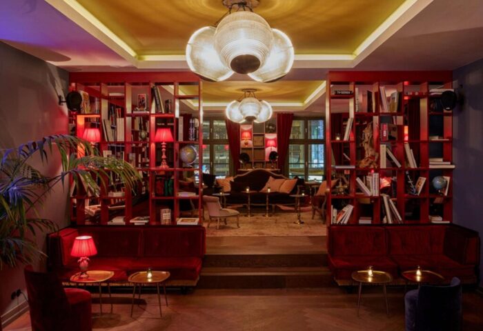 Lobby at the gay-friendly 25hours Hotel The Royal Bavarian. Red bookshelves, velvet sofas, and warm lighting create a stylish, inviting space.