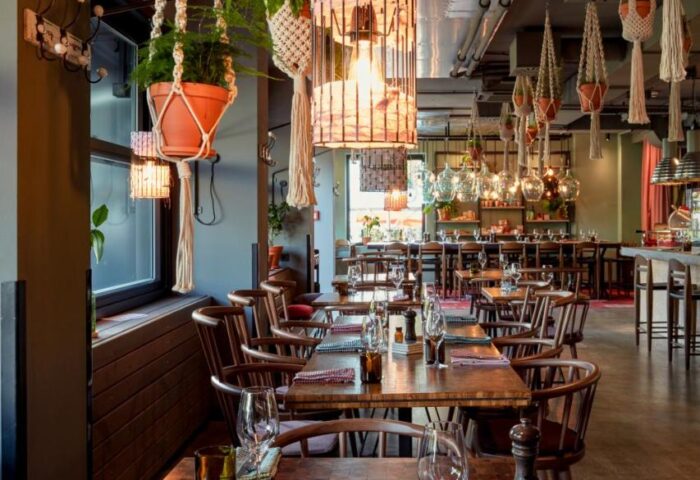 Dining area at 25hours Hotel beim MuseumsQuartier, a gay-friendly hotel. Tables, chairs, hanging plants, and unique lighting fixtures.