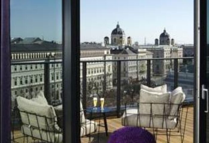View from 25hours Hotel beim MuseumsQuartier balcony. Gay-friendly hotel with city views, chairs, and drinks. Vienna travel.