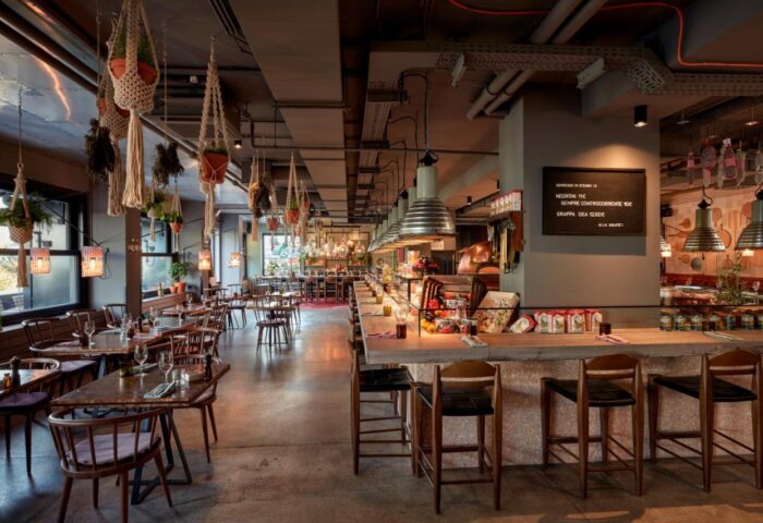 25hours Hotel beim MuseumsQuartier restaurant. Interior view of the gay-friendly hotel's dining area with tables, bar, and hanging plants.