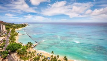 Aerial view of Waikiki Beach near Hyatt Regency, a gay-friendly hotel. Palm trees, ocean, and Diamond Head create a tropical paradise.