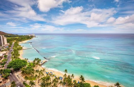 Aerial view of Waikiki Beach near Hyatt Regency, a gay-friendly hotel. Palm trees, ocean, and Diamond Head create a tropical paradise.