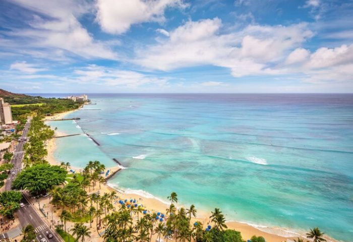 Aerial view of Waikiki Beach near Hyatt Regency, a gay-friendly hotel. Palm trees, ocean, and Diamond Head create a tropical paradise.