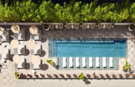 Aerial view of The Laylow Autograph Collection's pool area. This gay-friendly hotel features lounge chairs and lush greenery.
