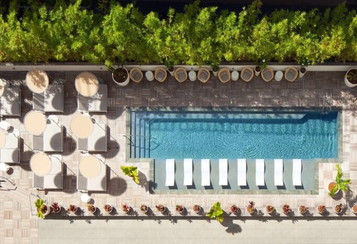 Aerial view of The Laylow Autograph Collection's pool area. This gay-friendly hotel features lounge chairs and lush greenery.