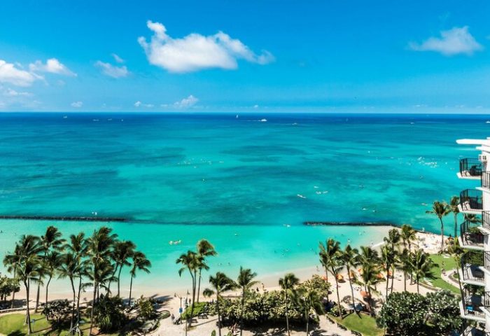 Aston Waikiki Beach Tower view. Gay-friendly hotel with ocean, beach, and palm trees. Perfect for gay men's travel in Waikiki.