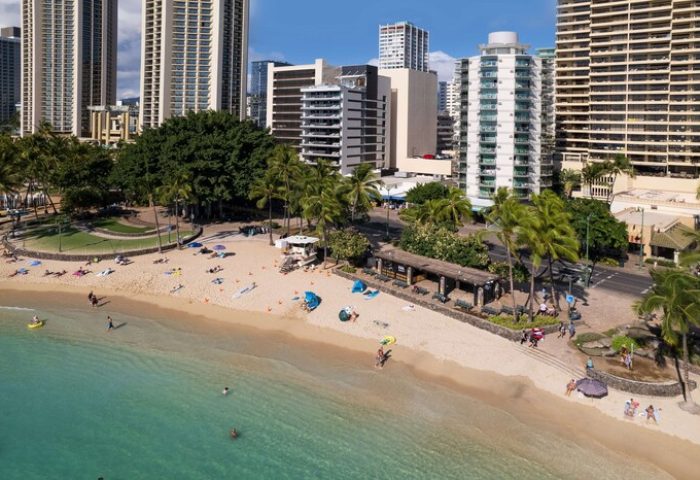 Waikiki Beach view near Aston Waikiki Circle Hotel, a gay-friendly hotel. Turquoise water, palm trees, and skyscrapers. A perfect gay travel destination.
