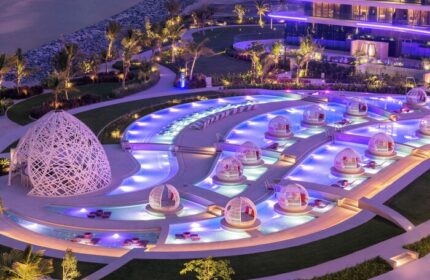 W Dubai - The Palm gay-friendly hotel. Aerial view of the pool area with cabanas, and purple lighting. Luxury travel destination.