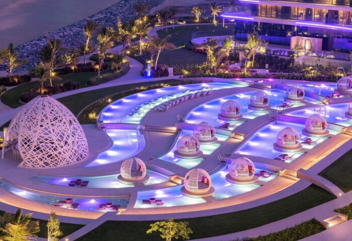 W Dubai - The Palm gay-friendly hotel. Aerial view of the pool area with cabanas, and purple lighting. Luxury travel destination.
