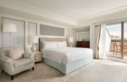 Shangri-La Bosphorus, Istanbul gay-friendly hotel room. Balcony with city view, bed, chair, lamps, and dresser. Upscale gay travel.