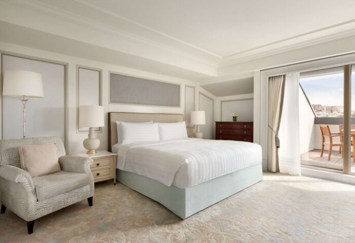 Shangri-La Bosphorus, Istanbul gay-friendly hotel room. Balcony with city view, bed, chair, lamps, and dresser. Upscale gay travel.