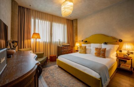 Soho House Istanbul gay-friendly hotel room. Stylish bedroom with a yellow bed, vintage furniture, and warm lighting. Luxury gay travel.